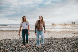 Two girls laughing and walking on the beach with colourful Noz sunscreen on their noses. Noz believes it can go anywhere that you can.